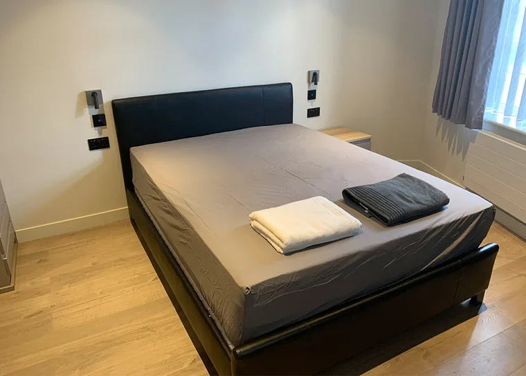 Double bed beside a window in a furnished studio